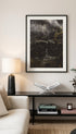 Living room with a framed artwork, lamp, books, and flowers on a table.
