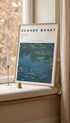 Framed artwork of Claude Monet's 'Water Lilies' on a windowsill with a candle and decorative elements.